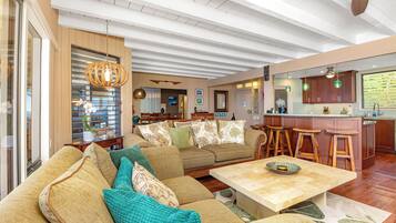 A spacious living area with a large sofa, a coffee table, and a kitchen area with bar stools.