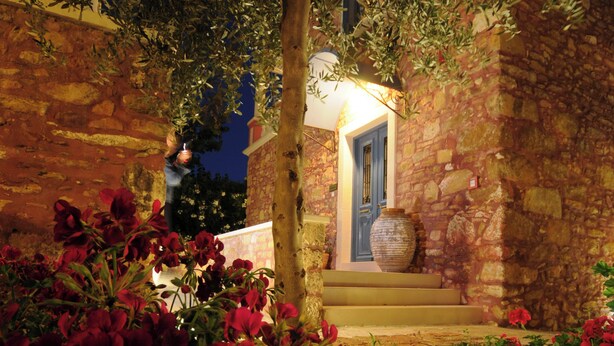 A stone building with a blue door, a large vase, and red flowers in the foreground. - Dine on the Generous Veranda at a Rustic Stone Getaway (Platanias)