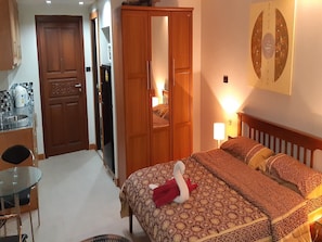 Ein Hotelzimmer mit einem Bett, einem Holzschrank, einem Schreibtisch mit Stuhl und einem kleinen Tisch.