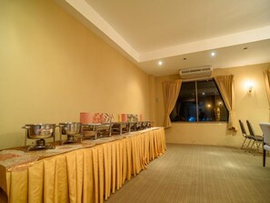 Ein Konferenzraum mit einem langen Tisch, der mit einer gelben Tischdecke bedeckt ist, und verschiedenen Catering-Artikeln ausgestattet.