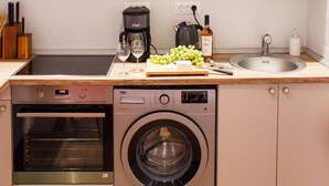 A compact kitchen with a built-in oven, washing machine, and coffee maker. - Apartment - Cismigiu Gardens (Bucharest)