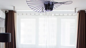 A modern living room with a red sofa, a red armchair, a round coffee table with cups and a tray, and a unique black ceiling light fixture. - Apartment - Cismigiu Gardens (Bucharest)