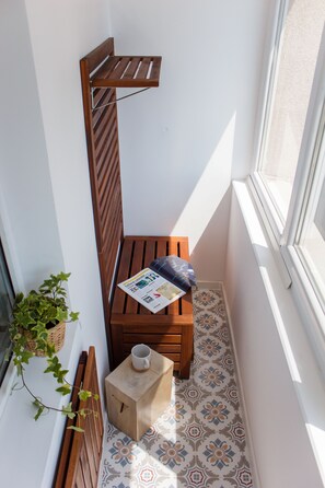 A small, narrow balcony with a wooden bench, a small table with a newspaper, a cup, and a potted plant. - Apartment - Cismigiu Gardens (Bucharest)