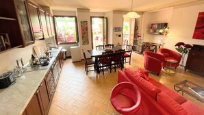 A spacious living area with a dining table, red sofa, and a kitchen area with cabinets and a countertop.