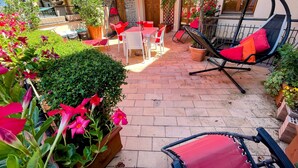 A patio with a table and chairs, a swing chair, and potted plants. - Central Spoleto Apartment With Large Sunny Terrace With Views (Spoleto)
