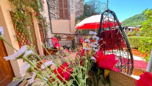 A courtyard with a red umbrella, a hanging chair, and potted plants.