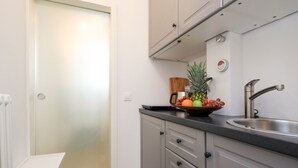 Eine kleine Küche mit Spüle, Obstschale und Kaffeemaschine.