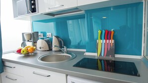Een moderne keuken met een wasmachine, een magnetron en een fruitschaal op het aanrecht.