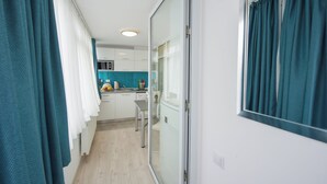 Een moderne keuken met witte kastjes, een aanrecht en een raam met turquoise gordijnen.