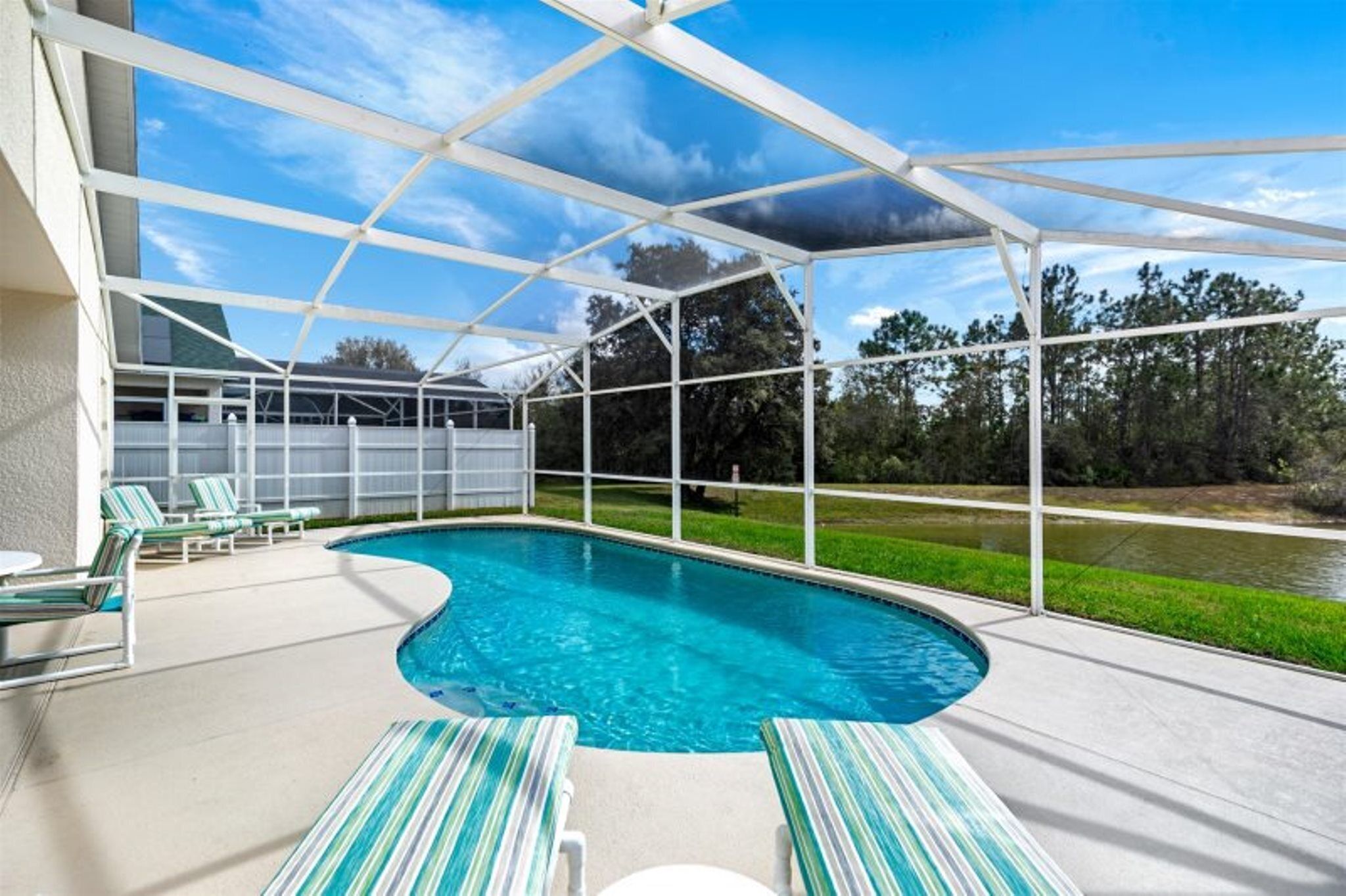 A covered outdoor swimming pool with lounge chairs and a view of the surrounding landscape.