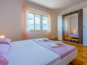 Une chambre à coucher avec un lit, une fenêtre avec des rideaux, un miroir et une vue sur le ciel.