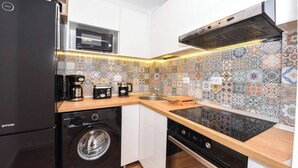A compact kitchen with a refrigerator, microwave, coffee maker, and washing machine.