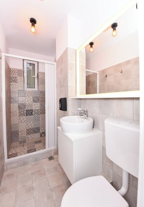 Un baño con ducha, lavamanos e inodoro.