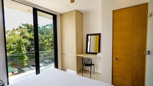 Ein Schlafzimmer mit einem großen Bett, einem Schreibtisch mit Stuhl, einem Kleiderschrank und einem Deckenventilator.