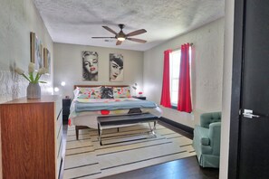 Un dormitorio con cama, mesita de noche y ventilador de techo.