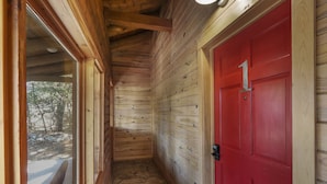 A wooden interior hallway with a red door marked "1" and a window overlooking a snowy outdoor area. - Resort Suite Across the Street from Market Days - Sleeps 4! (Wimberley)