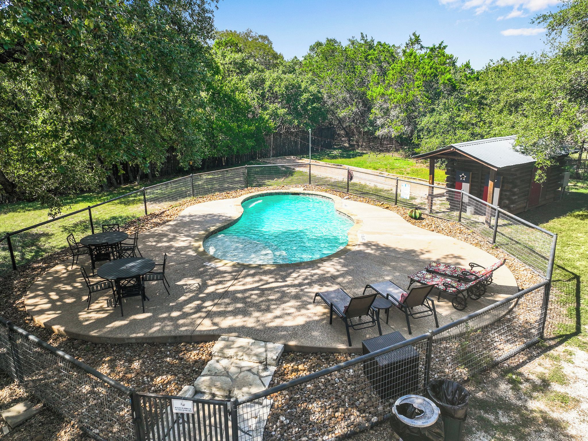 Patio trasero con piscina, rodeado por una valla y amueblado para el exterior.