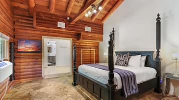 Ein Schlafzimmer in einer Blockhütte mit einem Himmelbett, Steinböden, Holzbalken an der Decke und einem Gemälde von einem Sonnenuntergang.