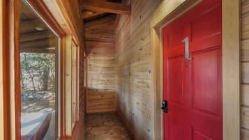 A wooden interior hallway with a red door marked "1" and a window overlooking a snowy outdoor area.