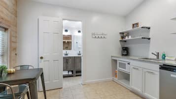 A kitchen with white cabinets, a countertop, a sink, and a coffee maker.
