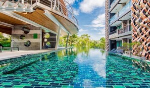 A modern hotel with a swimming pool, featuring a unique architectural design with circular windows and a patterned exterior wall. - Pool Front Sexy Studio Fully Furnished Apartment (Patong)