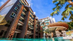 Ein modernes Hotel mit Pool, mehreren Balkonen und einem markanten architektonischen Entwurf, der sich durch vertikale Strukturen und ein rundes Gebäude auszeichnet.