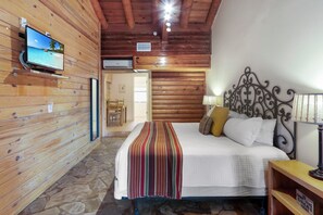 Habitació amb panells de fusta, un llit, un televisor fixat a la paret i un sòl de pedra.