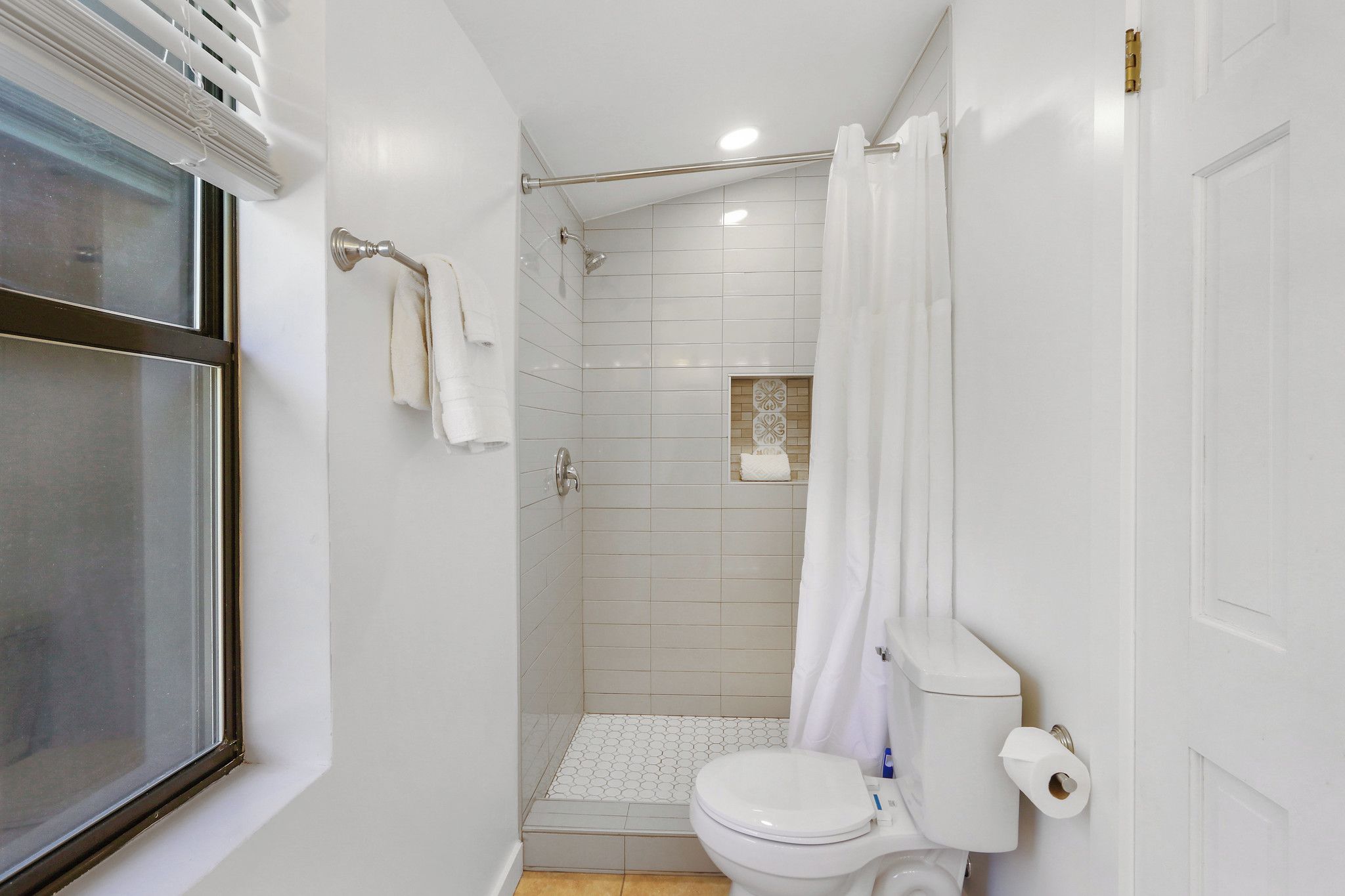 Un baño pequeño con inodoro, ducha y ventana.
