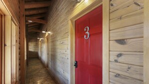 A hallway with wooden walls and a red door marked with the number 3. - Hotel Style Suite with Resort Pool, Fire Pit, and Grill (Wimberley)