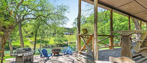 Une terrasse extérieure avec un barbecue, des chaises et une table en pierre.