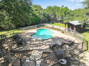 Patio trasero con piscina, rodeado por una valla y amueblado para el exterior.