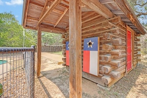 Une cabane en bois rustique, avec une clôture en métal au premier plan.
