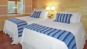 Ein Doppelbett mit weiß-blauer Streifenwäsche, zwei Nachttische mit Lampen und ein Fenster mit Holzjalousien.