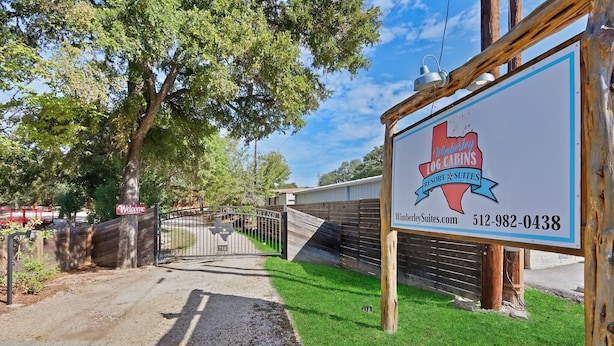 A sign for Wimberley Togg Cabins Resort Suites with a contact number and website.