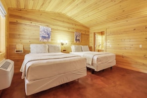 Ein Schlafzimmer einer Holzhütte mit zwei Betten, einem Heizgerät und Wandlampen.