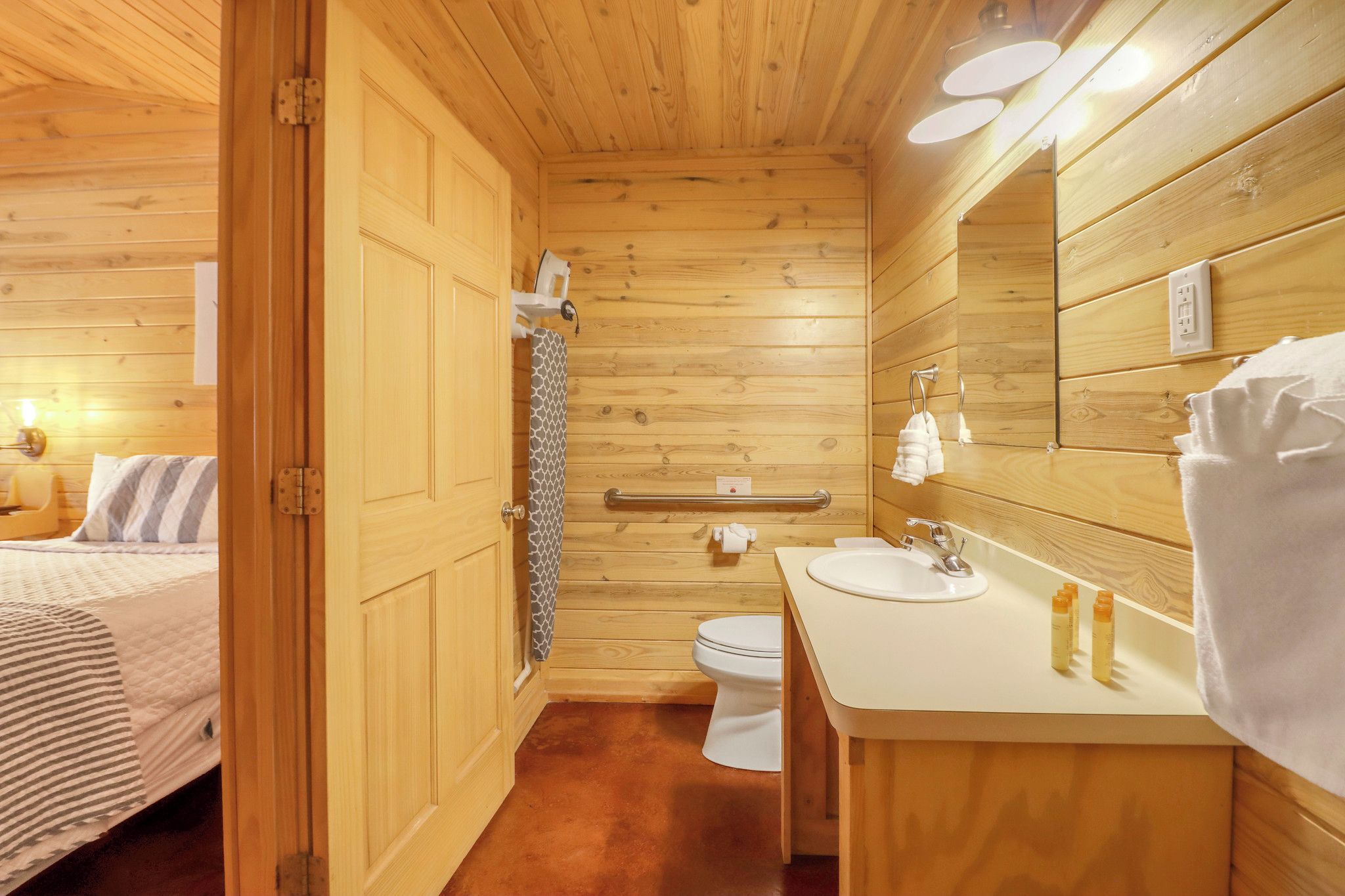 A wooden interior with a bed, a toilet, and a sink.