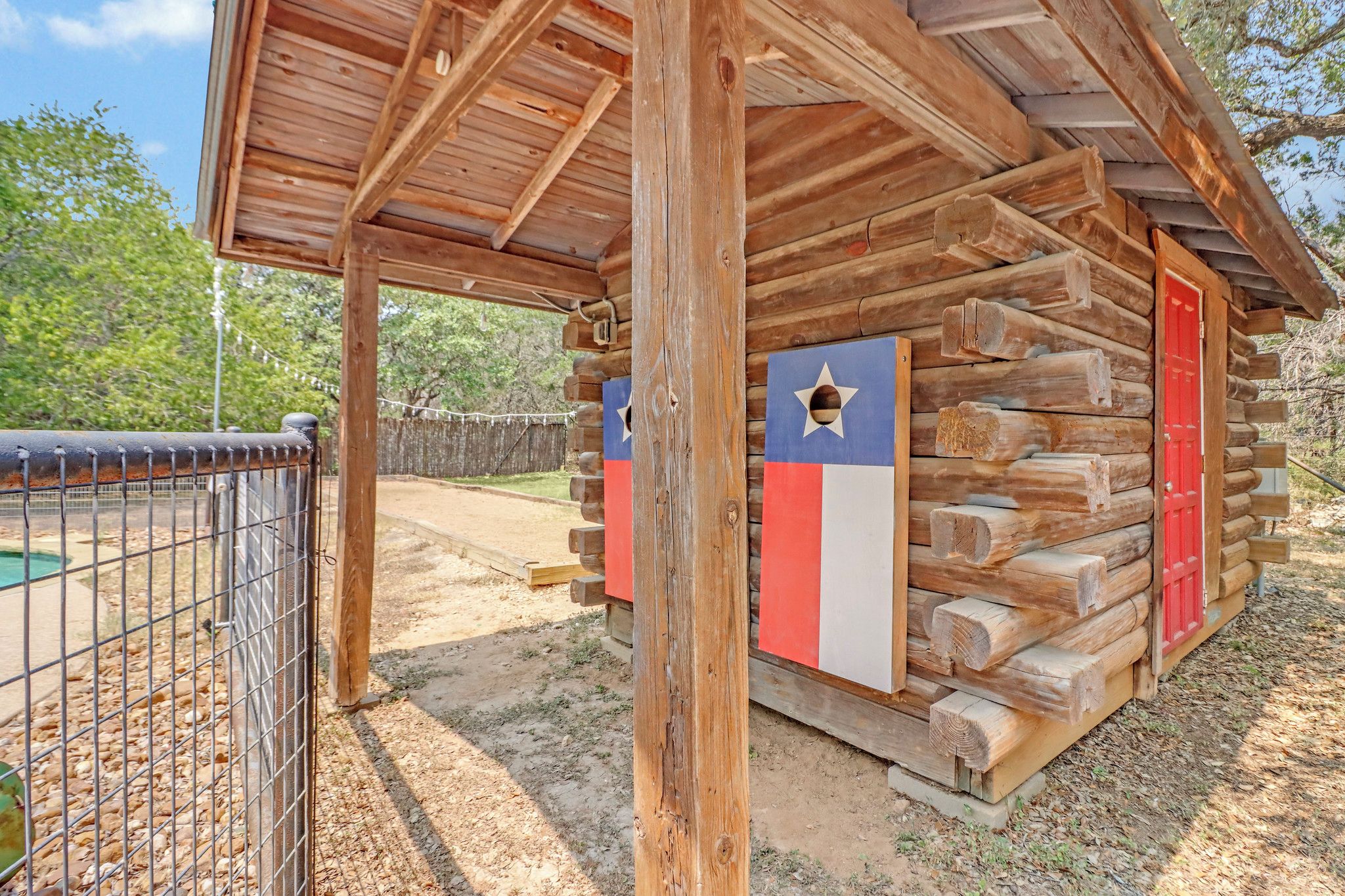 A rustic wooden cabin with a metal fence in the foreground.
