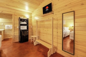 A wooden cabin interior with a black refrigerator, a microwave, a shelf with cups and a coffee maker, a bench, and a large mirror. - Resort Style Swimming Pool, Fire Pit, Grill, and Bocce Ball! (Wimberley)