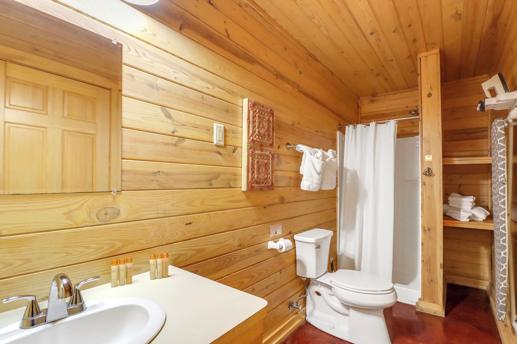 Baño de cabaña de madera con lavabo, inodoro y cortina de ducha.