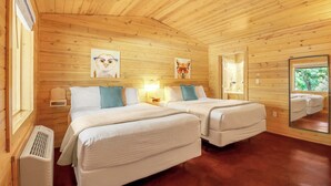 Una cabaña con dos camas, paredes de madera y un espejo grande que refleja el exterior.
