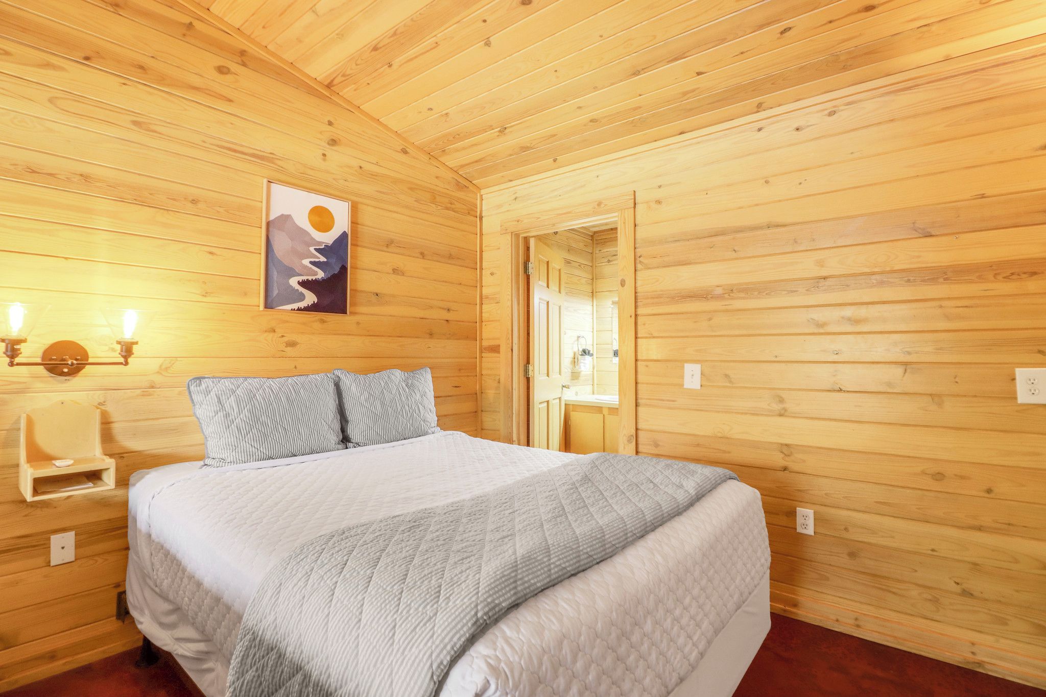Una stanza con rivestimento in legno, un letto, un comodino e un lampadario a parete.