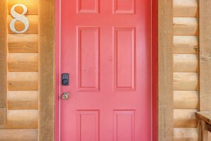 A red door with a keypad lock, a large number 8 sign, and wooden paneling on the walls.