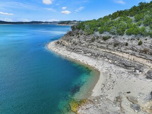 Un paisaje costero con aguas azules cristalinas, acantilados rocosos y vegetación escasa.