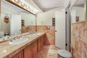 Un baño con lavamanos doble, tocador y un espejo grande.