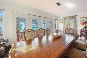 Un salón de conferencias con una gran mesa de madera, seis sillas tapizadas y amplias ventanas con vistas al exterior.