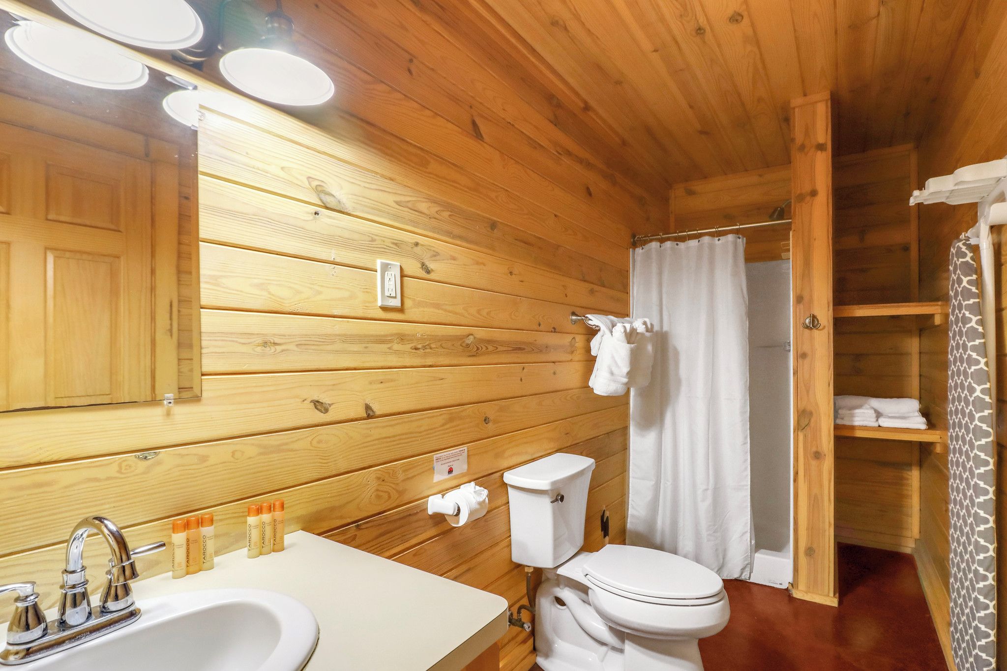 A wooden-paneled bathroom with a sink, toilet, and shower curtain.