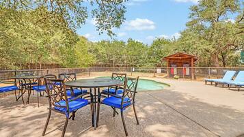 Ein Sitzbereich im Freien mit Tischen und Stühlen, ein kleiner Pool und eine Holzkonstruktion.