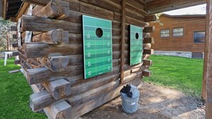 A rustic log cabin with a wooden exterior and a green football field layout on the wall.