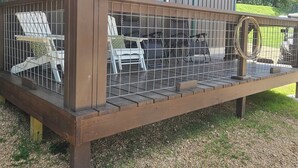 Eine Holzterrasse mit einer Pergola, Sitzgelegenheiten im Freien und Blick auf eine grüne Landschaft.
