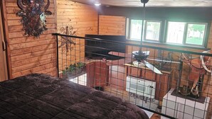 Ein rustikales Zimmer im Chalet-Stil mit einem großen Bett, Holzwänden, einem aufgehängten Tierkopf und einem Balkon mit Blick ins Freie.